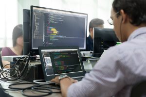 Asian Outsource Developer Looking Screen Sitting At Desk Working Laptop Computer Mobile Application Software Real Office
